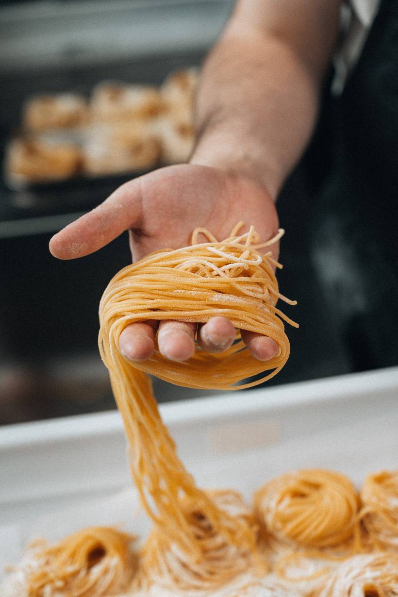 Een nest verse tagliatelle in de hand